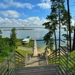 Idealne miejsce na mazury na weekend. Drewniane schody prowadzą do jeziora, gdzie cumuje statek.