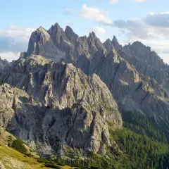 Majestatyczne szczyty Cadini di Misurina w Dolomitach, ostre jak zęby, wznoszą się ku błękitnemu niebu z chmurami.
