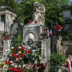 Grób Chopina na cmentarzu Père Lachaise w Paryżu, ozdobiony kwiatami i flagami.