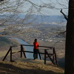 Widok z białowodzkiej góry na dolinę z rzeką i miasteczkiem. Kobieta w czerwonej bluzie podziwia panoramę.