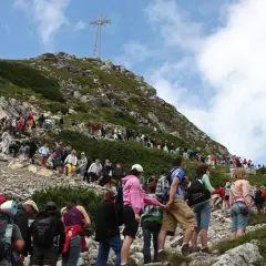 Tłum turystów na skalistej trasie na Giewont. W oddali widoczny krzyż.