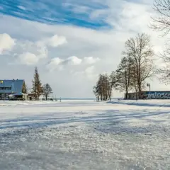 Zimowy krajobraz w Giżycku na Mazurach. Zamrożone jezioro, budynki i drzewa pokryte śniegiem.