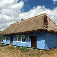 Skansen w Maurzycach: niebieska chata z tradycyjnym, strzechowym dachem.