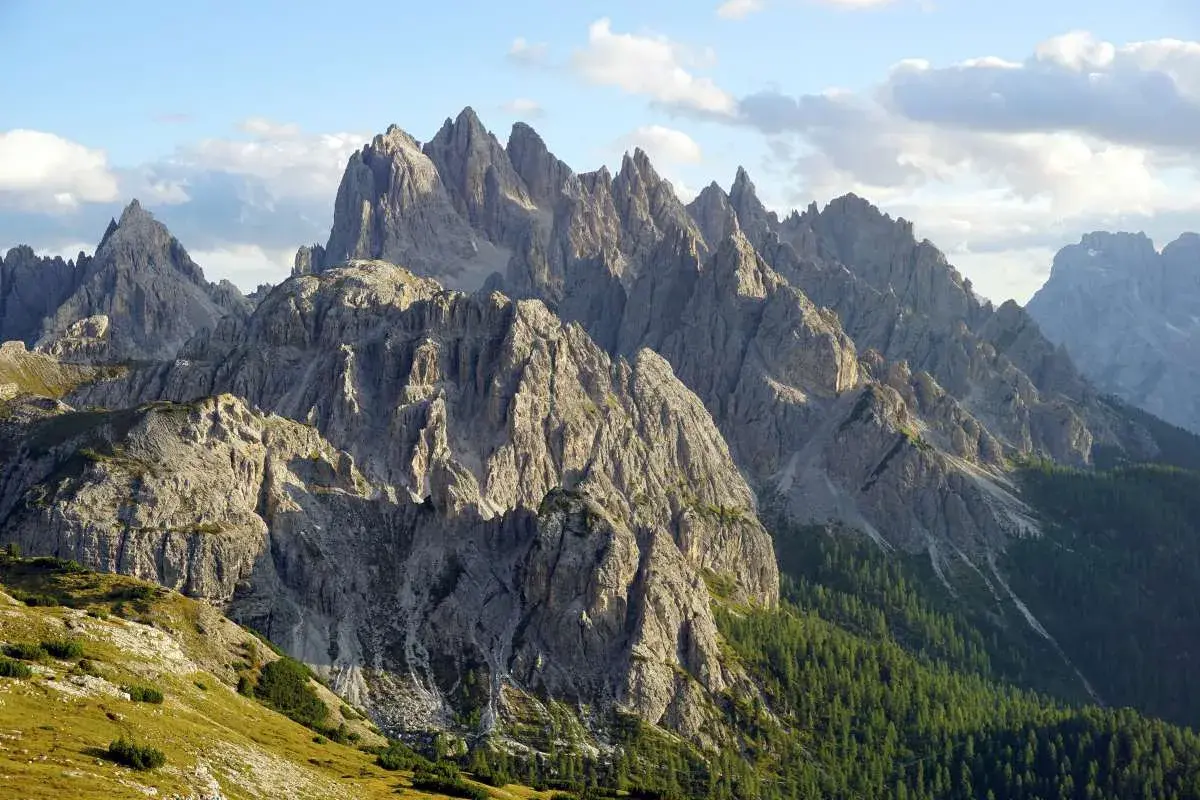 Majestatyczne szczyty Cadini di Misurina w Dolomitach, ostre jak zęby, wznoszą się ku błękitnemu niebu z chmurami.