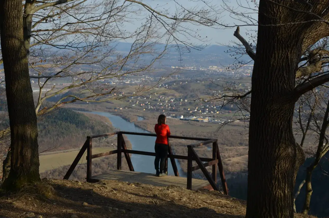 Widok z białowodzkiej góry na dolinę z rzeką i miasteczkiem. Kobieta w czerwonej bluzie podziwia panoramę.