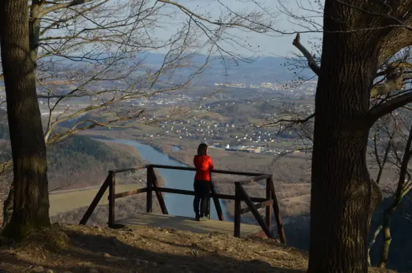 Widok z białowodzkiej góry na dolinę z rzeką i miasteczkiem. Kobieta w czerwonej bluzie podziwia panoramę.